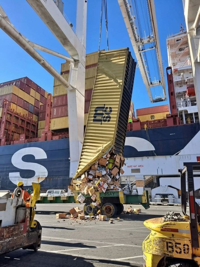 Contenedor en operación portuaria con mercancía derramada durante maniobra de carga